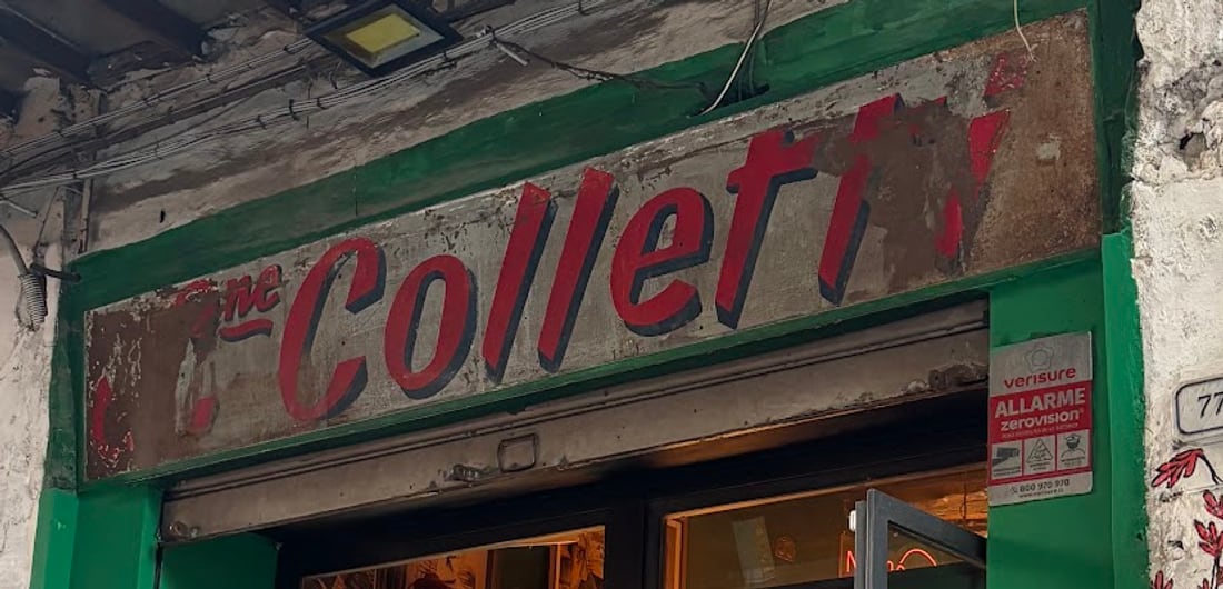 L'insegna Colletti dipinta a mano in rosso sopra la porta verde