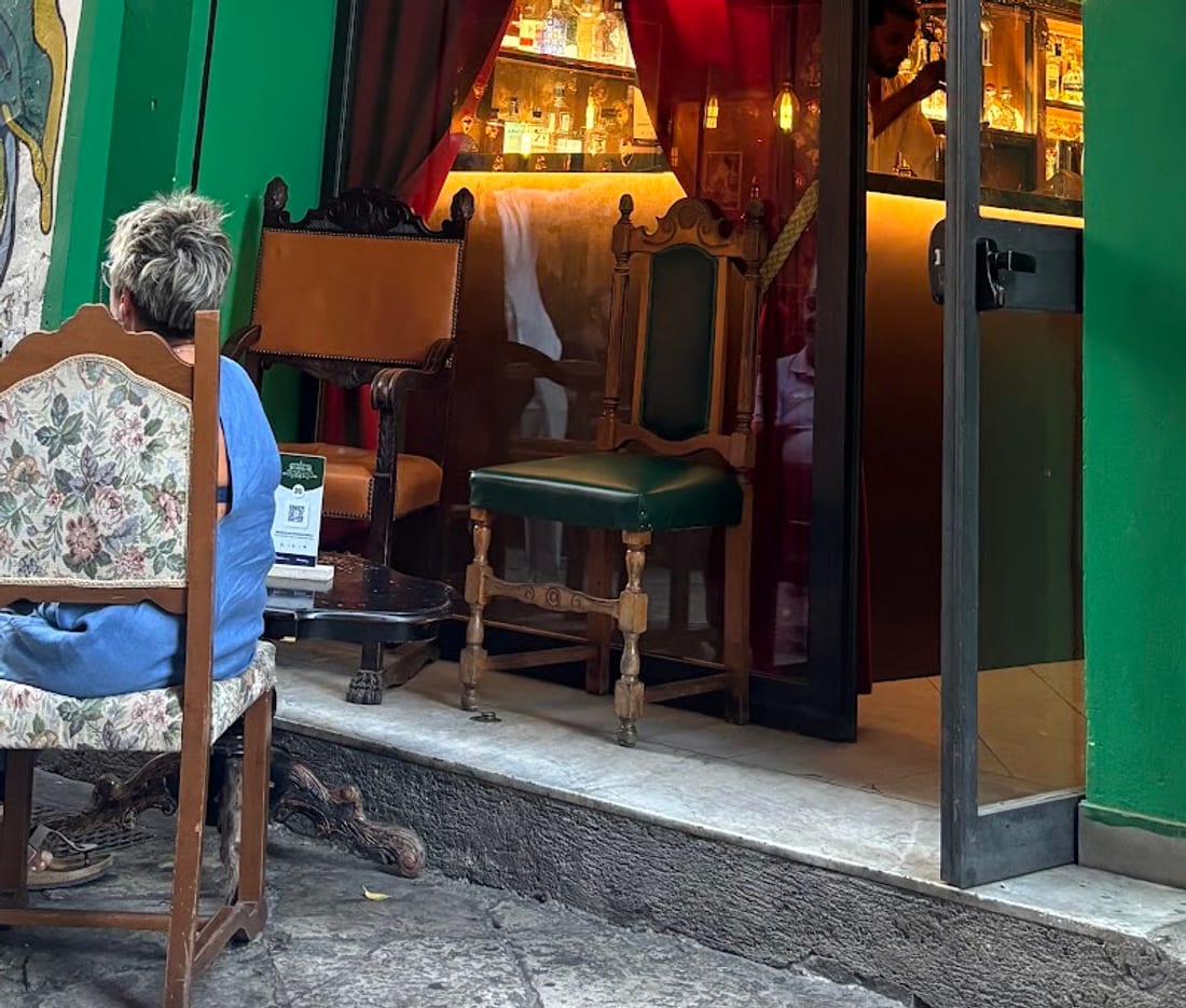 Poltrone e sedie antiche sui basoli davanti alla porta aperta del locale
