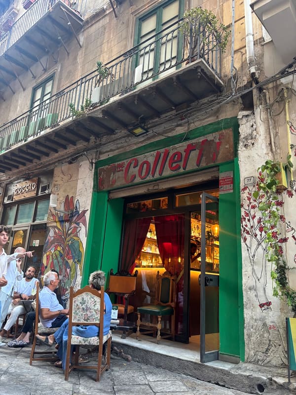 La vetrina verde di Botteghe Colletti in via Alessandro Paternostro, con l'insegna dipinta a mano e le poltrone antiche sui basoli